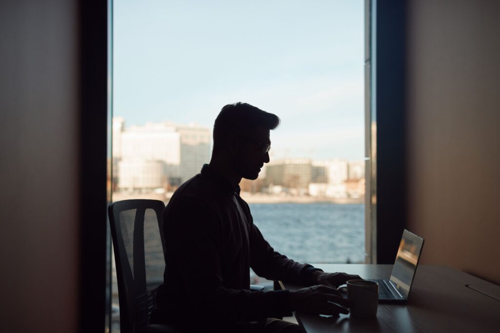 A man with a laptop and a coffee mug, receiving work-life balance coaching.